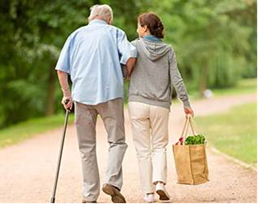 Elderly man and caregiver walking down the road